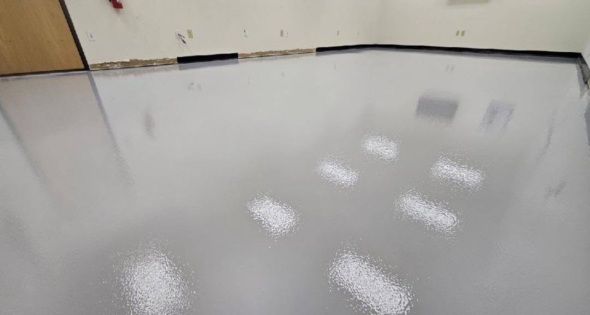 White solid color epoxy floor with a black cove base