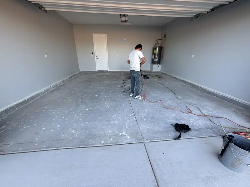 Crew member preparing a bare garage slab before coating