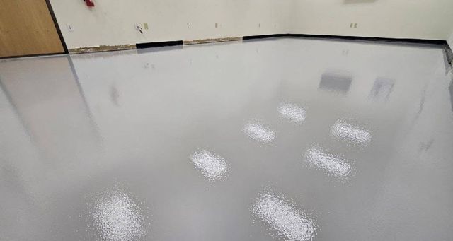 White solid color epoxy floor with a black cove base