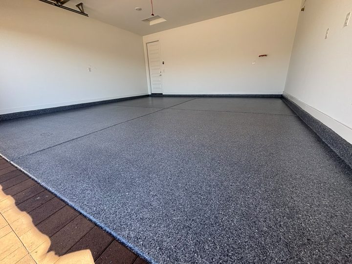 Dark grey flake epoxy garage floor with a cove base, seen from the door